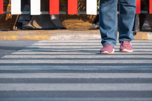 Front view of human legs walking across the street on zebra crossing in public area photo