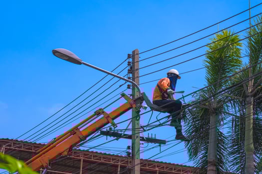 Low angle view of crane truck lifting electrician lineman to cut off tree branches that are too tall for safety electrical transmission system and beautiful landscape photo