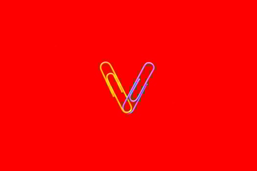 Yellow and blue paper clips on blood red background. photo