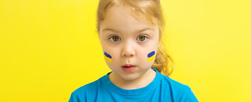 A girl with a painted Ukrainian flag of yellow and blue on her cheeks photo