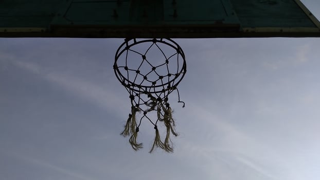 Bottom view of dim green old basketball hoop and broken net with a dark background of morning sky in the public sport field. photo
