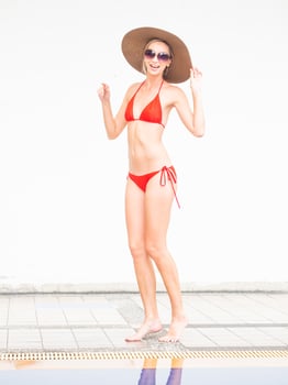 sexy girl happy girl in red bikini wear hat and sunglasses near swimming pool with white wall. photo