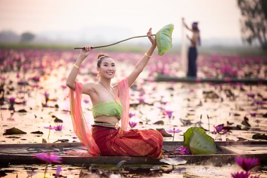 Young Asian women in Traditional dress in the boat and pink lotus flowers in the pond.Beautiful girls in traditional costume.Thai girl in retro Thai dress, Thai girl in traditional dress costume photo