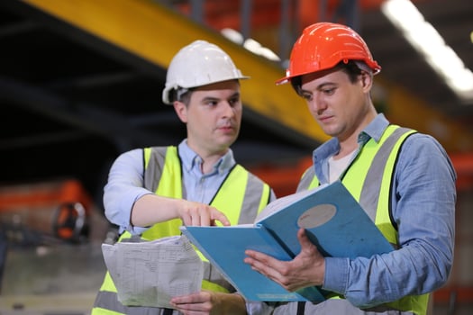 Men industrial engineer wearing a safety helmet while standing in a heavy industrial factory. The Maintenance looking of working at industrial machinery and check security system setup in factory. photo