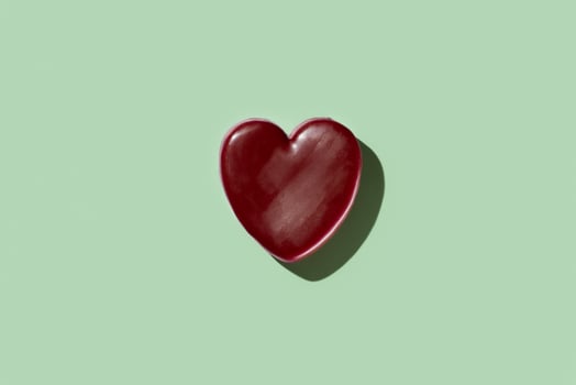 Red wax heart on green background photo