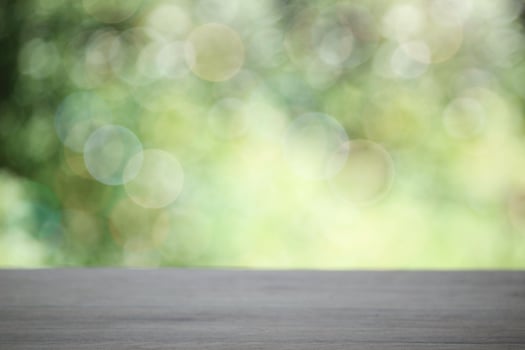 Empty wooden table top planks with beautiful nature blurred green leaf background under sunlight photo