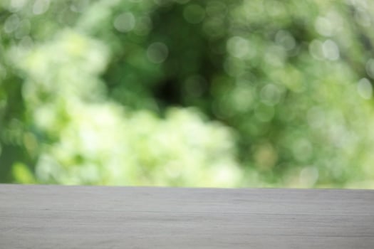 Empty wooden table top planks with beautiful nature blurred green leaf background under sunlight photo