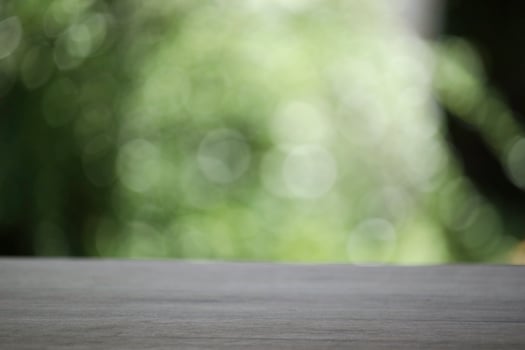 Empty wooden table top planks with beautiful nature blurred green leaf background under sunlight photo