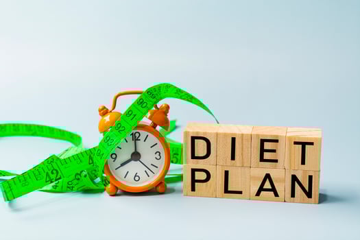 Diet plan text on wooden block cube with measure tap and orange clock. photo