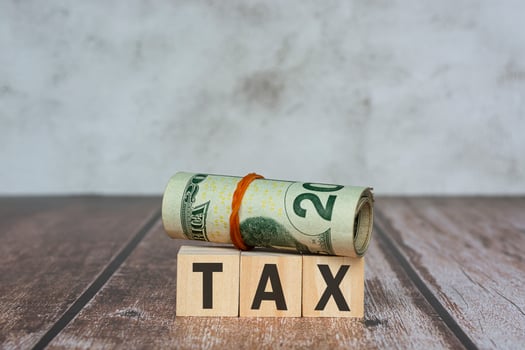 Tax text on wooden blocks and banknotes on wooden table. photo