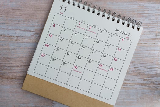 White November 2022 calendar on wooden background with daily holiday events. photo