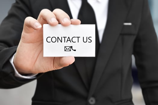 Businessman hand holding business card with the message contact us. Idea for customer support hotline people connect photo