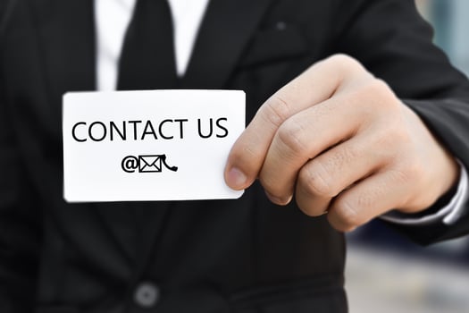 Businessman hand holding business card with the message contact us. Idea for customer support hotline people connect photo