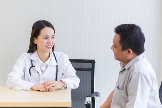 Young Asian professional female doctor good mood smile suggests health solutions to elderly male patients in the hospital examination room. photo