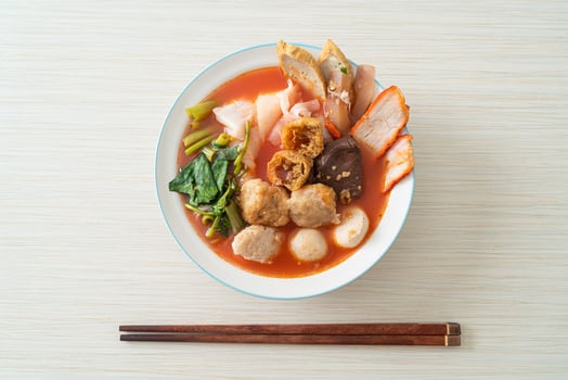 noodles with meatballs in pink soup photo