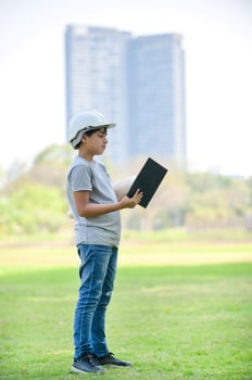 A half-Thai-Indian boy wearing a helmet holds a blueprint And expecting that in the future will be an engineer to build buildings photo
