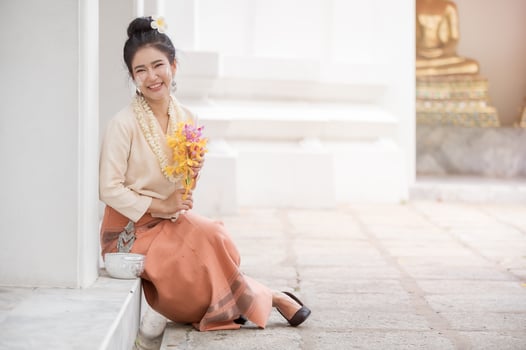 Thai woman in Thai dress resting in a temple After having used water soluble powder on cheeks for fun in celebrating Songkran water festival photo