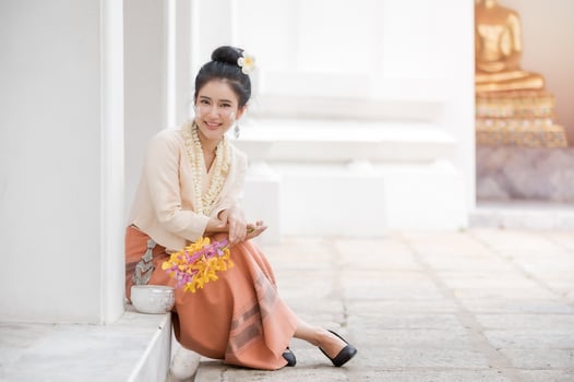 Thai woman in Thai dress resting in a temple After having used water soluble powder on cheeks for fun in celebrating Songkran water festival photo