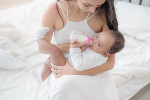 A beautiful Asian woman, carrying her newborn baby with love and cherish, and feeding her with happiness photo