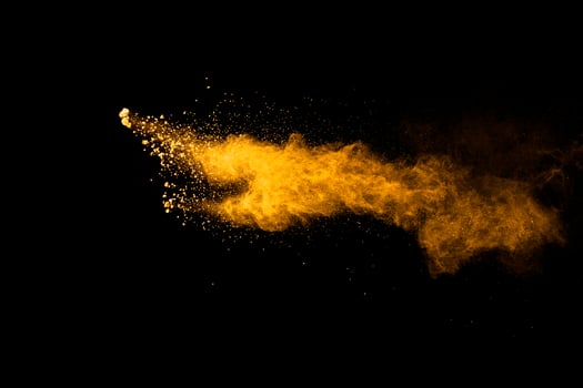 Abstract explosion of orange dust on black background.Freeze motion of orange powder burst. photo