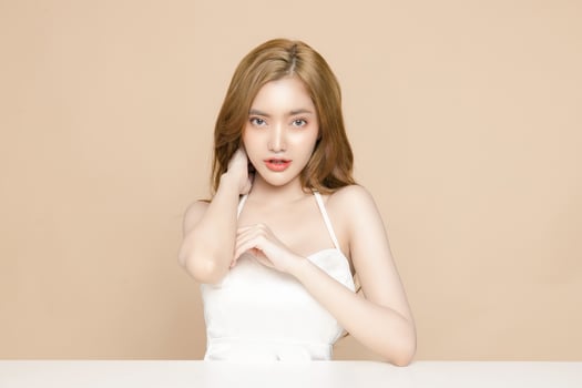 Cute young Asian woman wearing braces is feeling happy with clean fresh skin isolated over cream background. Plastic surgery Face care, Facial treatment, Cosmetology, beauty and spa, Women portrait. photo