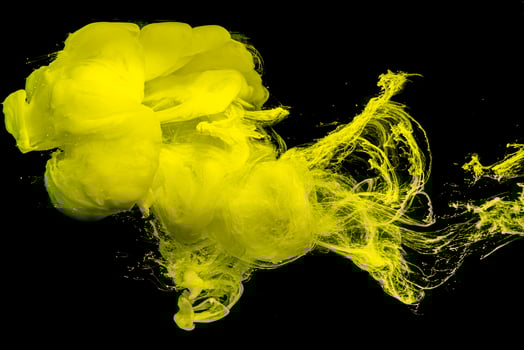 Yellow ink drop swirling on background. Cloud of acrylic ink.Color drops in water. photo