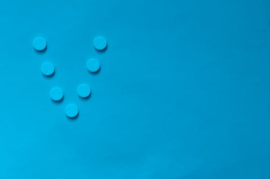 The letter V in the form of pills on classic blue background. photo