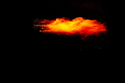 Red orange color powder explosion cloud isolated on black background. photo