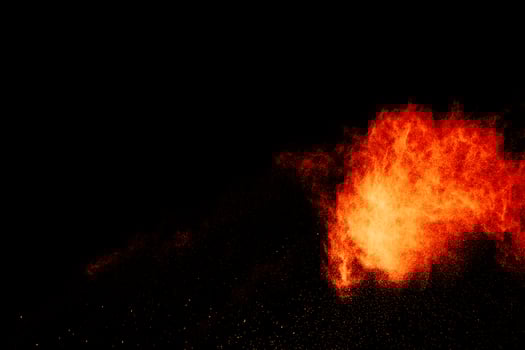 Red orange color powder explosion cloud isolated on black background. photo