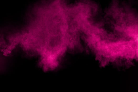 Explosion of pink color powder on black background. Splash of color powder dust on dark background. photo