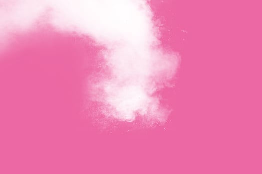 Abstract white powder explosion on pink background. Freeze motion of white dust splattered. photo