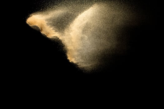 Sand explosion isolated on black background. Freeze motion of sandy dust splash. photo