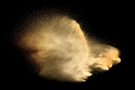 Sand explosion isolated on black background. Freeze motion of sandy dust splash. photo