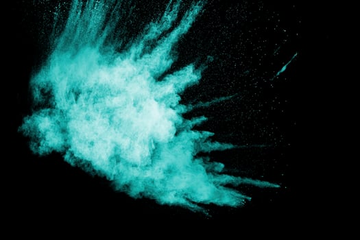 Green blue dust explosion on black background. Freeze motion of color powder splashing. photo