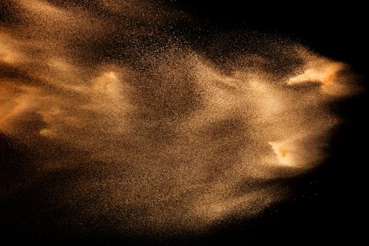 Dry river sand explosion isolated on black background. Abstract sand cloud.Brown colored sand splash against dark background. photo