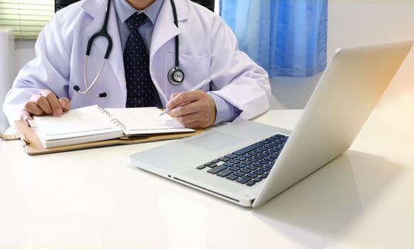 A doctor sitting at a desk with a laptop photo