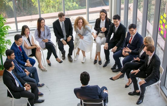 Group of people listening to experienced business professional helping them work out new corporate strategy. photo