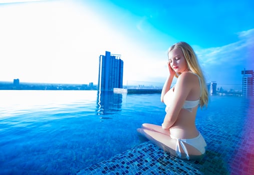 Young woman enjoying and relaxing at poolside. Slim young girl model in white bikini  by the pool. photo