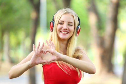 Beautiful blonde woman standing while listening music on headphone at park. photo