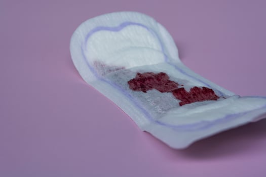 Menstrual blood on a sanitary pad on pink background. Flat lay photo