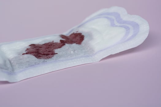 Menstrual blood on a sanitary pad on pink background. Flat lay photo