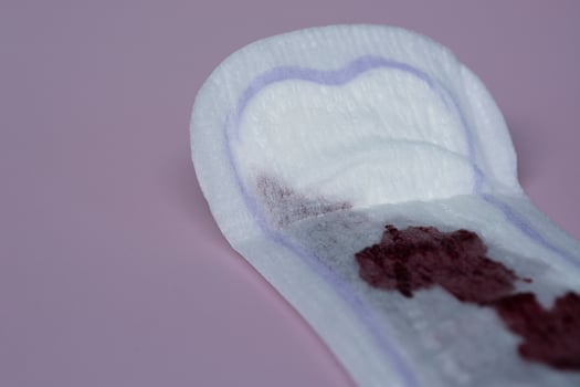 Menstrual blood on a sanitary pad on pink background. Flat lay photo