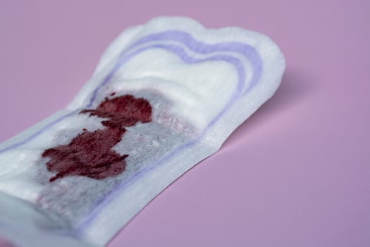 Menstrual blood on a sanitary pad on pink background. Flat lay photo