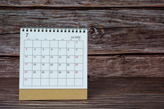 White July 2022 calendar on wooden desk. 2022 new year concept. photo