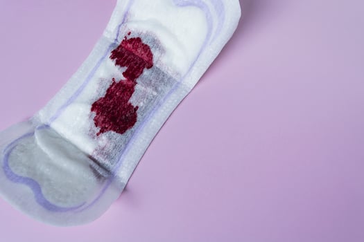 Menstrual blood on a sanitary pad on pink background. Directly above. Flat lay photo