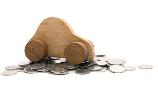 Wood car on a pile of coins on white background photo