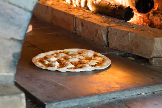 Thin crust pizza baking in wood fired oven photo