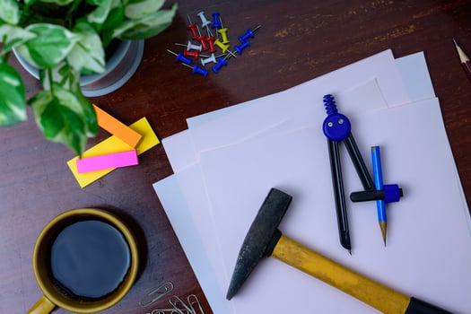 Coffee, hammer, file, pencil and office supplies. Placed beside a tree on a wooden table. photo