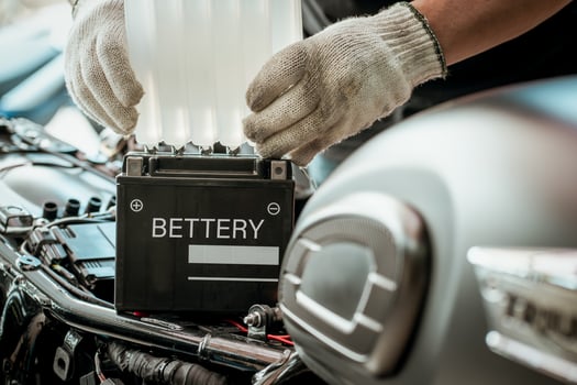 mechanic replaces motorcycle battery and holding Acid pack or sealed battery electrolyte pack to prepare for fill up battery,motorcycle maintenance and service and repair concept . selective focus photo