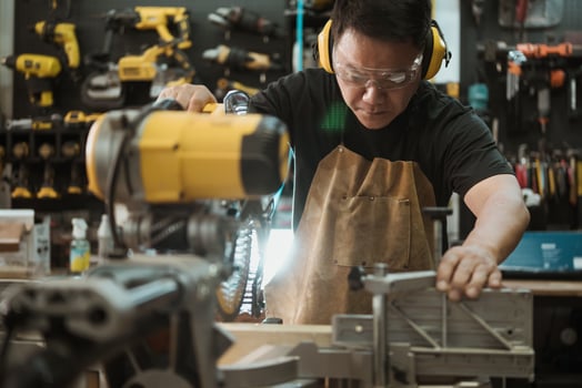 Carpenter cutting wooden with a miter saw or circular saw in shop, woodworking repair and construction tool concept ,selective focus photo
